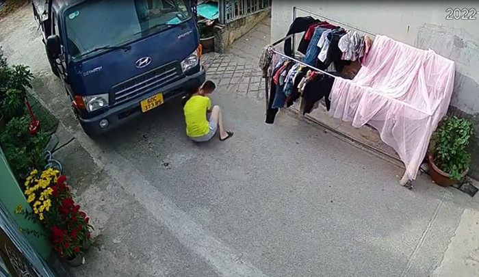 Người phụ nữ hoảng hốt lao ra, giải cứu bé trai dưới gầm xe tải. 