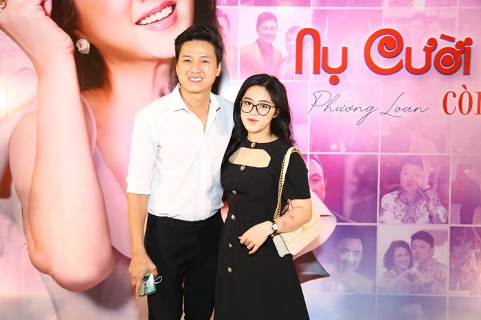 Quách Ngọc Tuyên trong trang phục áo sơ mi giản dị, sánh đôi cùng bà xã dễ thương với đôi răng khểnh duyên dáng. 