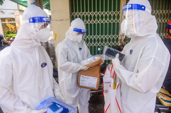 Nhân viên y tế phát thuốc cho F0 điều trị tại nhà ở quận 8, TP.HCM - Ảnh: QUANG ĐỊNH