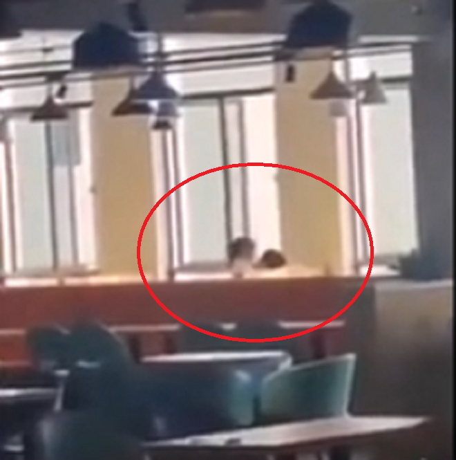 Cô gái ngồi lên người bạn trai rồi liên tục 'nhún nhảy' giữa quán ăn. Ảnh cắt từ clip