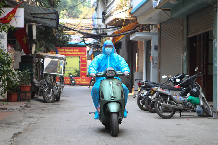 Tình nguyện viên sử dụng xe máy làm phương tiện di chuyển tới những con ngõ nhỏ, ngách bé... giao thuốc cho F0 điều trị tại nhà - Ảnh: HÀ QUÂN