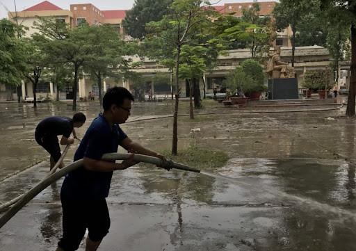 Thầy cô giáo tiến hành vệ sinh sân trường, lớp học sau khi nước rút. Nguồn ảnh: Báo Thanh Niên&nbsp;
