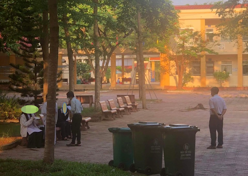 Các học sinh bị bắt ra ghế đá sân trường ngồi ăn dưới sự giám sát của thầy Phó hiệu trưởng