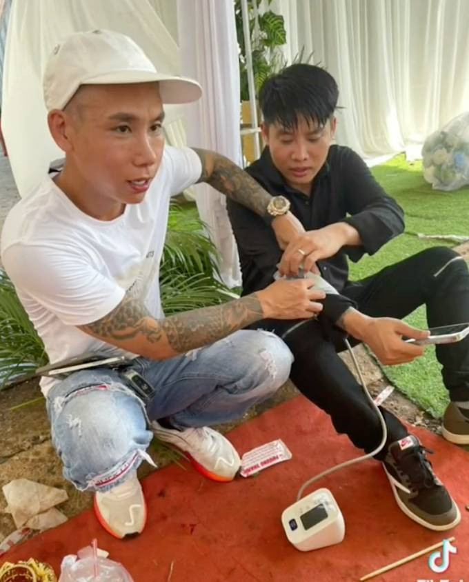 Chú rể phải ngồi nghỉ ngơi và được bạn hỗ trợ đo huyết áp sau khi đeo số vàng khủng