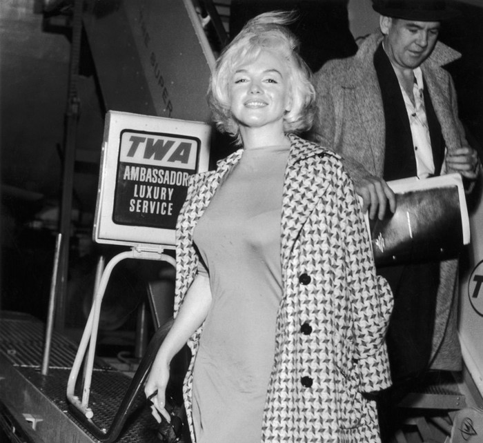 Đến sân bay LaGuardia vào năm 1961, Monroe thể hiện thần thái quý cô sang trọng trong một chiếc váy dài quá đầu gối với áo khoác len choàng qua vai.