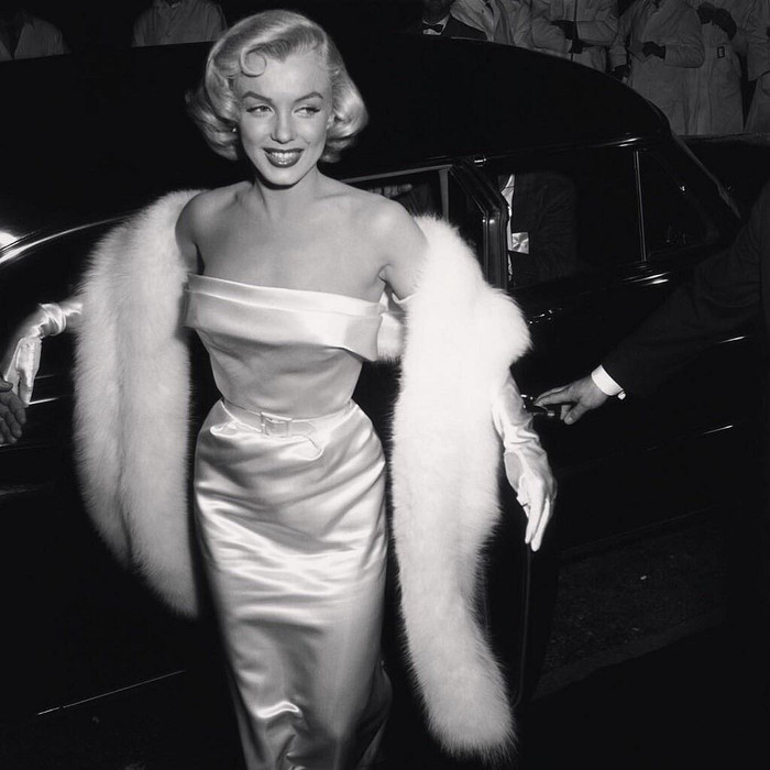 Tham dự buổi ra mắt phim 'There No Business like Show Business' năm 1954, Monroe rạng rỡ bước trên thảm đỏ trong bộ váy quây satin trắng và một chiếc áo choàng lông thú. Kiểu trang phục với chi tiết thắt eo, bao tay gợi tình giúp nữ diễn viên khẳng định đẳng cấp 'bom sex' nổi tiếng nhất thế giới.