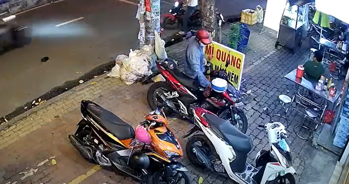 Nam thanh niên áo xanh, mũ bảo hiểm đỏ tiếp cận và bẻ khóa chiếc xe máy