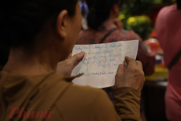 Nhiều phụ huynh đã chuẩn bị sẵn bài khấn cùng lễ vật để đến Văn Miếu. Ảnh: Báo Phụ Nữ.