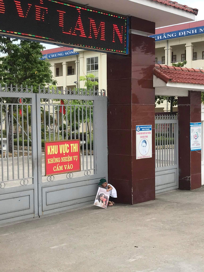 Khi chị gái đã vào phòng thi, bé trai đứng bên ngoài cổng trường vẫn lén nhìn qua cánh cửa cổng