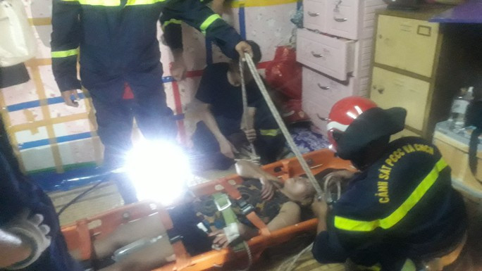 Lực lượng chức năng quyết định phá cửa sổ và đưa nạn nhân xuống bằng bộ dây cứu nạn cứu hộ trên cao bên ngoài cửa sổ. Ảnh: Người Lao Động