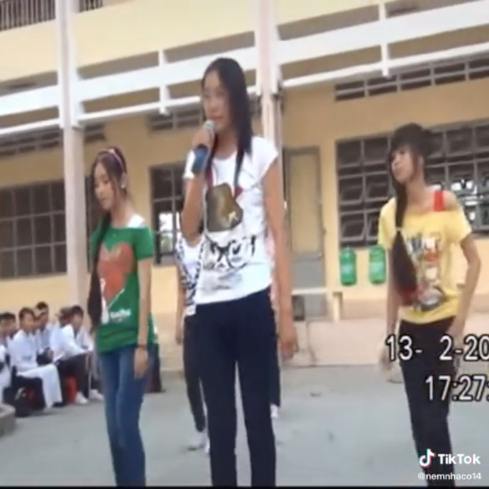 Nam Em mặc áo thun trắng với quần jeans bó sát. Cô tự tin trình diễn ca khúc Nhớ lắm trong một buổi văn nghệ trường.