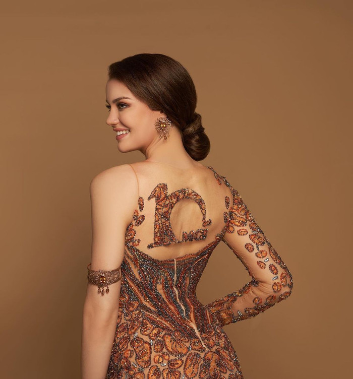 Điểm nhấn của outfit chính là logo kỷ niệm 10 năm của Miss Grand International.