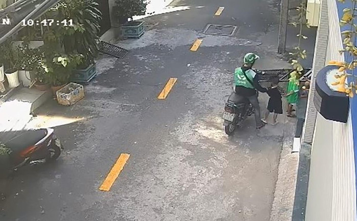 Nam thanh niên tiếp cận bé trai đang chơi đùa trên thềm nhà (Ảnh: Cắt từ clip - PLO)
