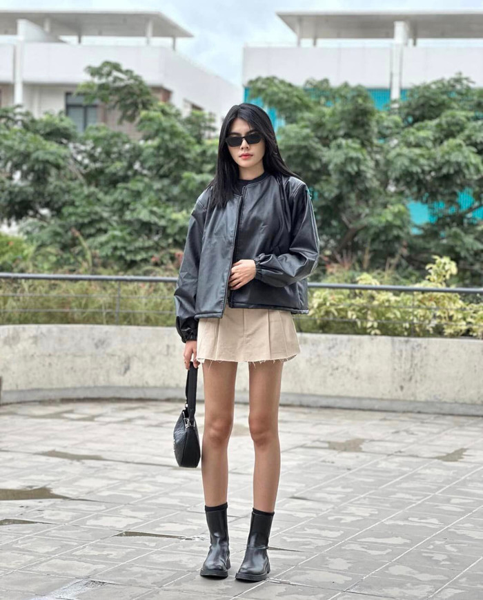 Nàng hậu có vẻ ngoài trẻ trung như các bạn học sinh khi diện chân váy chữ A màu be, phối với áo khoác da và boots da năng động.