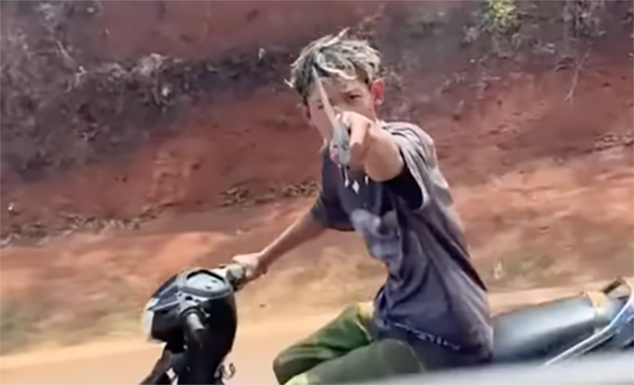 Thiếu niên đầu 2 thứ tóc cầm mã tấu tự chế chĩa vào phương tiện giao thông đe dọa. (Ảnh: Cắt từ clip)