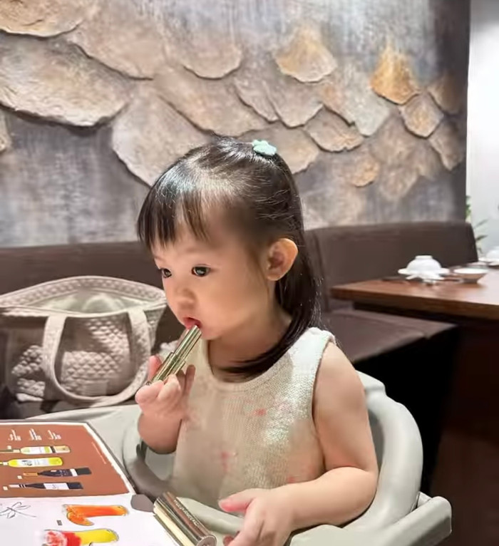 Suchin cầm thỏi son của mẹ tô lên môi, khuôn mặt liên tục có những biểu cảm dễ thương.