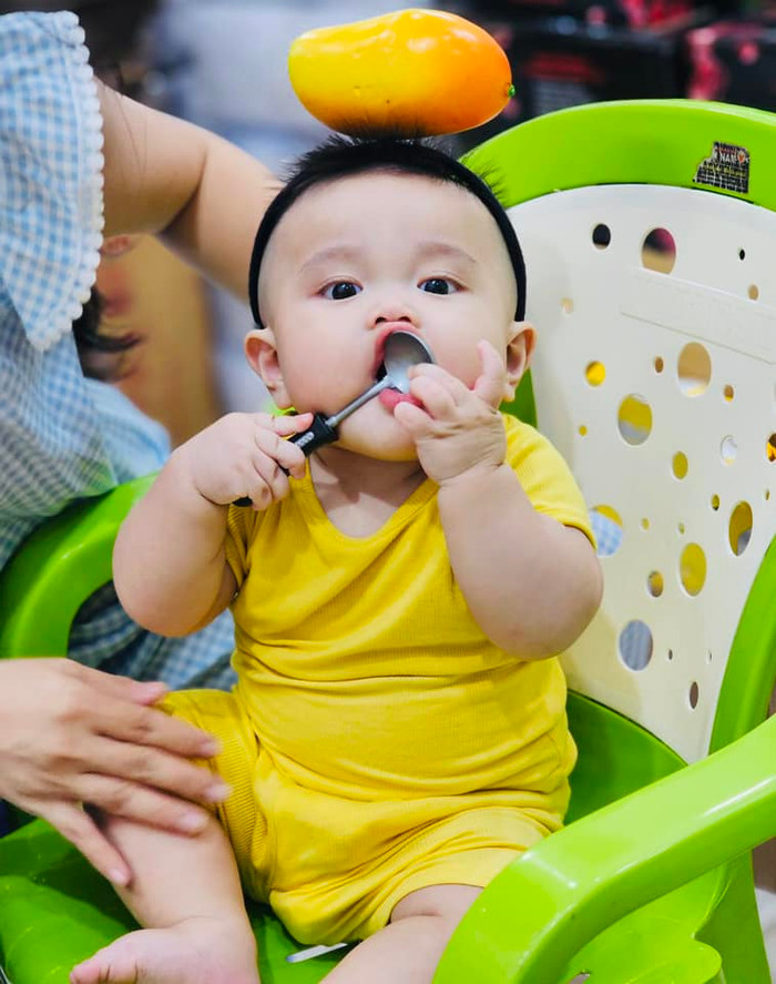  Nhóc tỳ được mẹ tạo hình cực dễ thương khi diện nguyên một outfit 'cây vàng' nổi bật kèm đó là quả xoài làm đồ vật trang trí cực cute. 