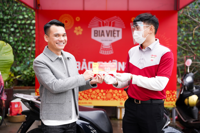 Khắc Việt cầm tờ phiếu xăng xe miễn phí, đây là một trong số các hoạt động tại Trạm Đoàn Viên Bia Việt nhằm hỗ trợ người về quê bằng xe máy.